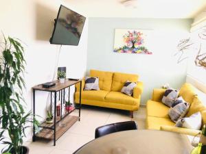 a living room with a yellow couch and a table at Tu refugio en CDMX cerca del Foro Sol y del AICM in Mexico City
