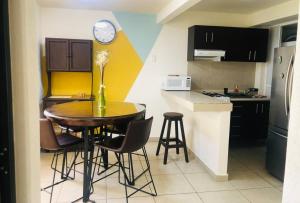 a kitchen with a table with chairs and a clock on the wall at Tu refugio en CDMX cerca del Foro Sol y del AICM in Mexico City