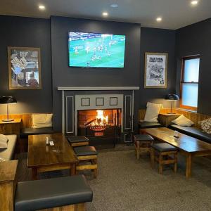 a living room with a fireplace and a tv on the wall at The George Hotel Bathurst in Bathurst