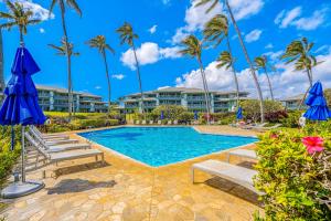 a pool at the resort with palm trees at Poipu Sands 221 in Koloa