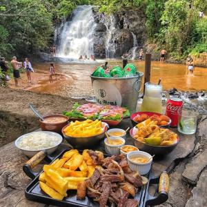 a table full of food with a waterfall in the background at Pousada chácara amarela - Analandia SP in Analândia
