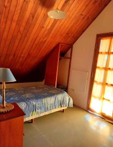 um quarto com uma cama com tecto em madeira e uma janela em ALQUILER TEMPORARIO, CHALET con PILETA, para 6 personas, SALTA, San Lorenzo em Salta