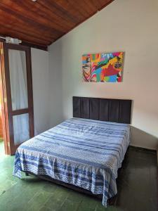 uma cama num quarto com um quadro na parede em Casa em condominio no Pero - Cabo Frio em Cabo Frio