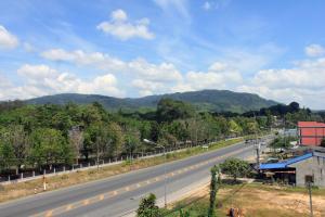 an empty highway with trees and mountains in the background at Cozy Rabbit Hotel in Thung Song