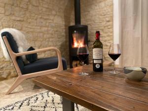 a bottle of wine sitting on a wooden table with two glasses at Picturesque renovated farmhouse with pool in Les Junies