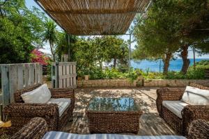 un patio con sillas de mimbre y una mesa de cristal en Artemisia Homes - Villa Cristina al Mare, en Marina Porto