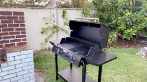 a barbecue grill in a yard with a fence at Lake Munmorah Motel in Lake Munmorah
