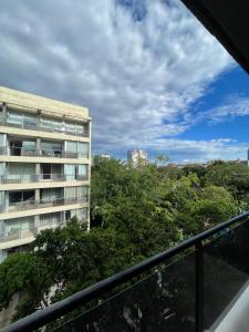 un balcón con vistas a un edificio y a los árboles. en Hermoso depto. 1 dormitorio- Asuncion- Villa Morra #504, en Asunción