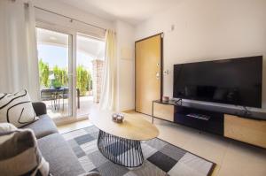 a living room with a couch and a tv and a table at Azul Beach by La Mata Beach in Torrevieja