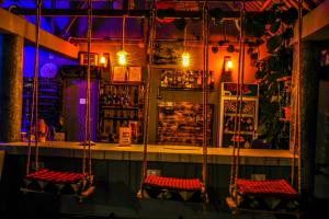 a bar with three swings in front of a bar at Home Villa Eco Boutique in Arusha