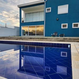 una casa azul con una piscina frente a ella en Casaazulvaleparaiba en Jacareí