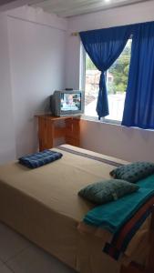1 dormitorio con 1 cama y ventana con TV en Hostal Casa del Viento Kitesurf & Adventure, en Calima