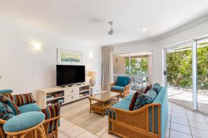 a living room with a couch and chairs and a television at Coral Horizons - Beachfront apartments in Palm Cove