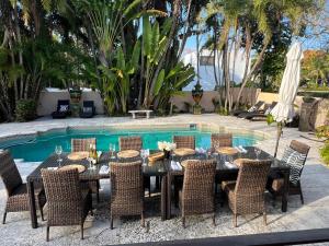 a dining table and chairs in front of a pool at Casa Belmar Miami in Miami