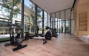 a gym with treadmills and ellipticals in a building with windows at S&N Hotel Wucheng in Yongxiu