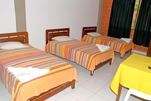 three beds in a room with a yellow table at Hotel Ambaibo in Rurrenabaque