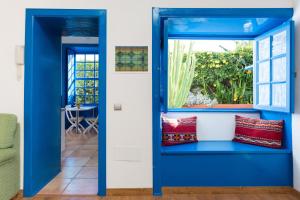 a blue room with a window and red pillows at La Hacienda Grande in Puerto de la Cruz