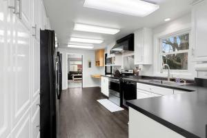 uma cozinha com armários brancos e um frigorífico preto em The Meadows em Green Bay