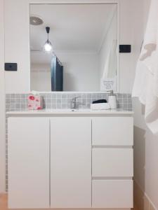 eine weiße Küche mit einem Waschbecken und einem Spiegel in der Unterkunft The Coastal Nest in Sussex inlet