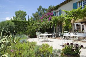 a patio with tables and chairs in a garden at Saint-Vincent in Saint-Tropez