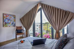 a bedroom with a laptop on a bed with a balcony at KP Villa Dalat in Da Lat