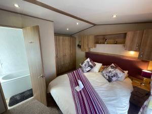 a small bedroom with a bed and a bath tub at Lakeside Retreat 2 with hot tub, private fishing peg situated at Tattershall Lakes Country Park in Tattershall