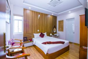 een slaapkamer met een groot bed en een houten muur bij Anh Thảo Hotel Quy Nhơn in Quy Nhon