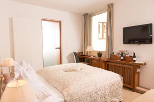 een slaapkamer met een bed, een bureau en een televisie bij Hotel Baseler Hof in Hamburg