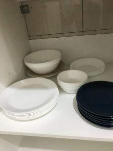 four white plates and bowls sitting on a counter at Elmina near Denai Alam, Saujana Utama with Wi-Fi & Netflix in Shah Alam
