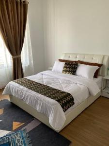 um quarto com uma cama grande com lençóis brancos e almofadas em Elmina near Denai Alam, Saujana Utama with Wi-Fi & Netflix em Shah Alam