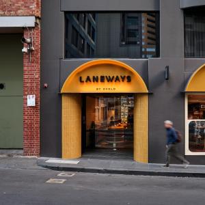 a man walking in front of a store with an orange sign at Laneways by Ovolo in Melbourne