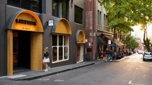 a woman walking down a street next to a building at Laneways by Ovolo in Melbourne