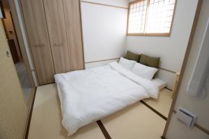 Cette petite chambre comprend un lit blanc et une fenêtre. dans l'établissement H2H Shinsaibashi, à Osaka