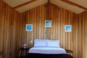 a bedroom with a bed in a wooden wall at Waterfront 'Jemadda' Family Lodge in Bream Creek