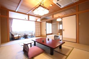 Cette chambre dispose d'une grande fenêtre et d'une table avec des chaises. dans l'établissement Tatsumikan, à Minakami