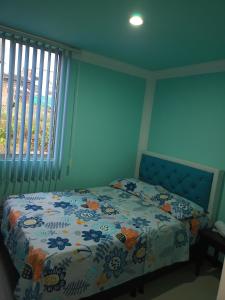 1 dormitorio con 1 cama con colcha de flores y ventana en SANDY APARTAMENTO en Santa Rosa de Cabal