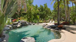 una piscina de agua con rocas y palmeras en Daintree Beach Resort, en Wonga