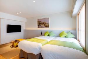 a bedroom with two beds and a flat screen tv at Hotel Claire Higasa in Himeji