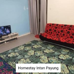 uma sala de estar com um sofá vermelho e um tapete em Homestay Intan Payung Mitc em Ayer Keroh