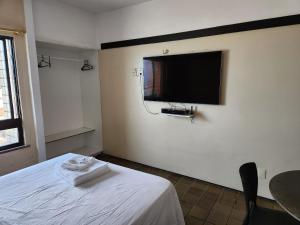 a bedroom with a bed with a tv on the wall at Tabajara flats in Fortaleza
