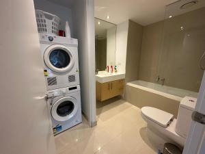 a bathroom with a washing machine and a toilet at Prima Tower Apartment Face to Crown by GoodLive in Melbourne