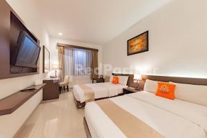 a hotel room with two beds and a flat screen tv at Hotel Alqueby Mitra RedDoorz in Bandung