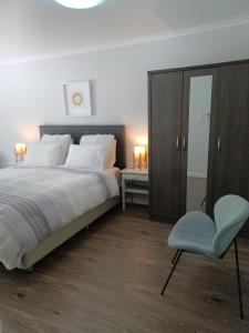 sypialnia z dużym łóżkiem i niebieskim krzesłem w obiekcie Tranquility on Verran w Auckland