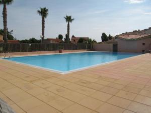 - une grande piscine dans une cour bordée de palmiers dans l'établissement Villa Saint-Cyprien, 3 pièces, 6 personnes - FR-1-106-34, à Saint-Cyprien