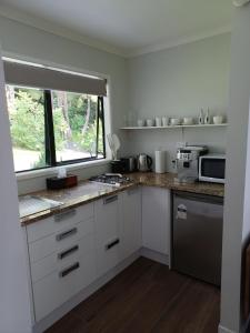kuchnia z białymi szafkami i oknem w obiekcie Tranquility on Verran w Auckland