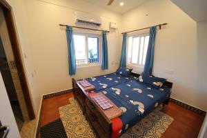 a bedroom with a bed with blue curtains at Le Pondy Home Stay in Pondicherry