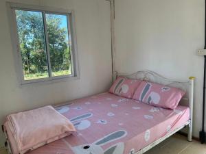 ein kleines Schlafzimmer mit einem rosa Bett und einem Fenster in der Unterkunft Khunkorn Fishing Farm Stay in Ban Mae Kon