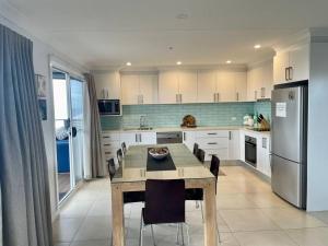 een keuken met een tafel, stoelen en een koelkast bij Summer Salt Beach House in Ulladulla