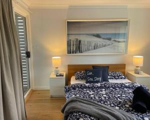 een slaapkamer met een bed en twee lampen en een foto bij Summer Salt Beach House in Ulladulla