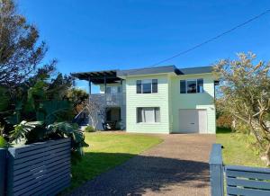 een groot wit huis met een hek ervoor bij Summer Salt Beach House in Ulladulla